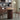 An Image of the Round Pedestal Dining Table in a Modern Dining Area in Rich Walnut Color, with Served Snacks and books on the table , and Three Solid Wood Dining Chairs