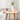 a round wooden end table with a flower vase and a book placed atop