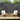 3 Piece Outdoor Furniture Set Image. 3 piece patio set with Cream Adirondack-Inspired Cushioned Chairs and Side Table in an outdoor setting.
