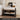a French provincial nightstand in a soft sand beige and ebony brown finish image. It displays some decorative items on the tabletop. 
