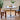 Image of the Round Pedestal Dining Table with Served Fruits, snacks and a Tea Pot on the Table Complemented by Two dining Chairs.