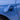 Close-up of a blue car's charging port with a lightning bolt symbol.