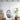 Hanging wicker chair with gray cushion in a room with white brick walls, a plant, and wooden furniture.