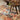 Decorative rug with floral patterns on a floor, wooden stool with foliage.