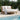 Round outdoor sofa with white cushions and a wooden frame by a poolside, surrounded by greenery.