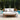 Round outdoor sofa with white cushions and a gray blanket by a poolside.