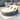 Outdoor lounge chair with cushions on a patio, featuring a small table with drinks and decor.