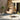Hanging egg chair with beige cushions on a patio area with a stone wall and plants.