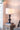 Table lamp with a white shade on a wooden side table in a room setting.