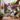 Woman sitting in a hanging chair on a patio with a fountain and purple flowers.