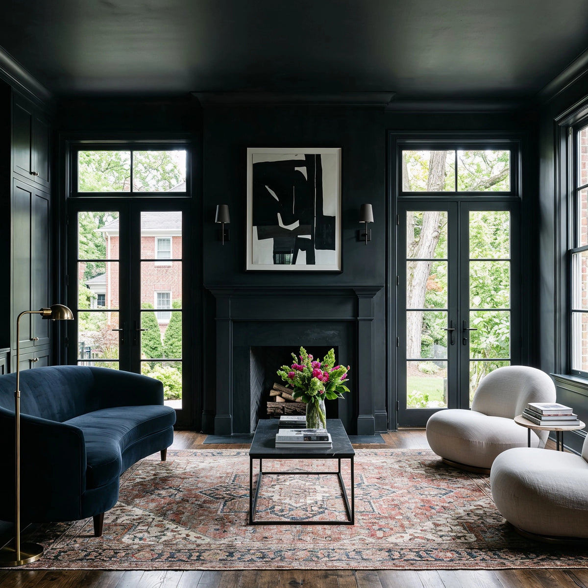 Black living room ideas with black-framed French doors, black fireplace, deep blue curved sofa, cream sculptural chairs, brass floor lamp, abstract artwork, and vintage patterned rug.