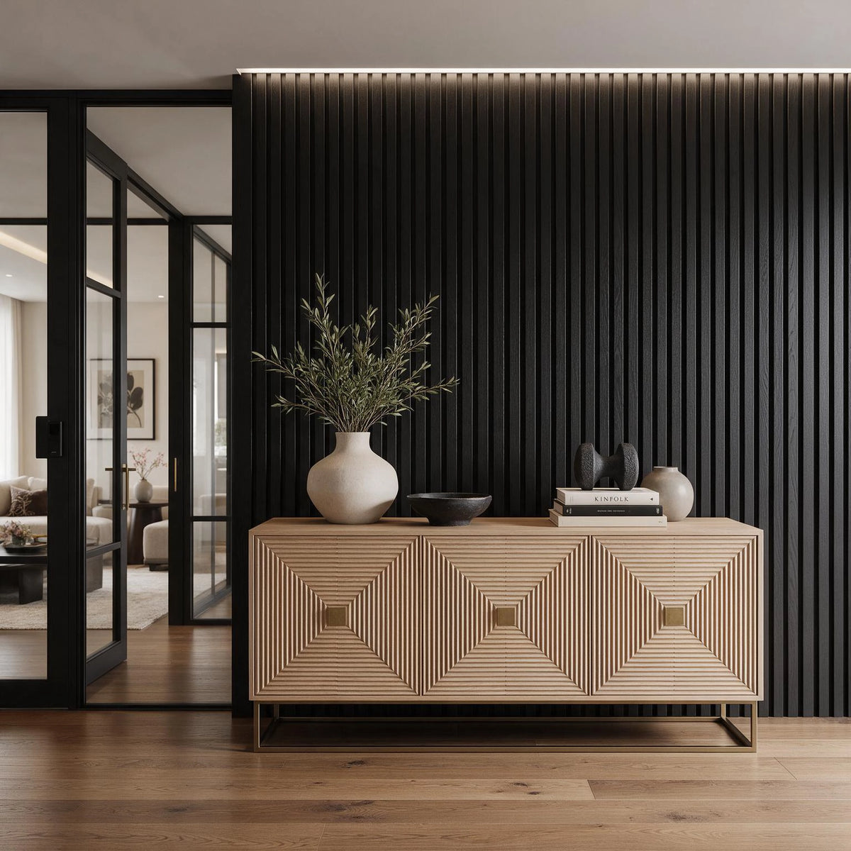 Black living room ideas with floor-to-ceiling black slatted wall paneling, light wood geometric credenza, neutral ceramics, greenery, and warm oak flooring.