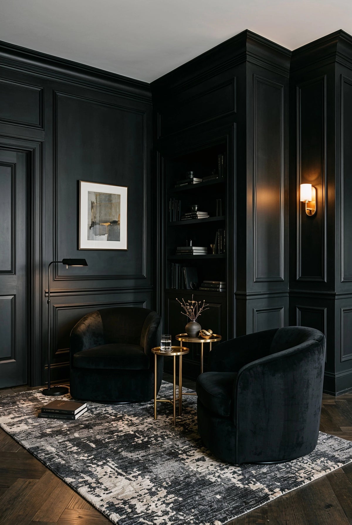 Black living room ideas with black paneled walls, black velvet lounge chairs, built-in shelving, brass nesting tables, warm wall sconce, and black-and-cream patterned rug.