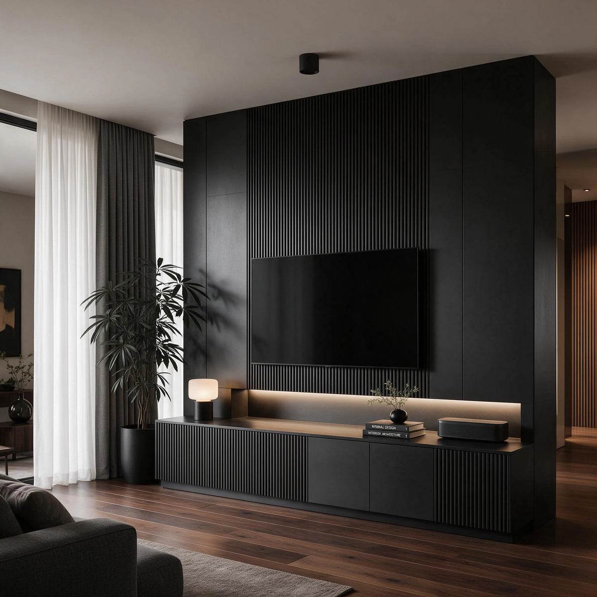 Black living room ideas with integrated black media wall, fluted paneling, concealed warm lighting, built-in cabinetry, wall-mounted TV, greenery, and warm wood flooring.