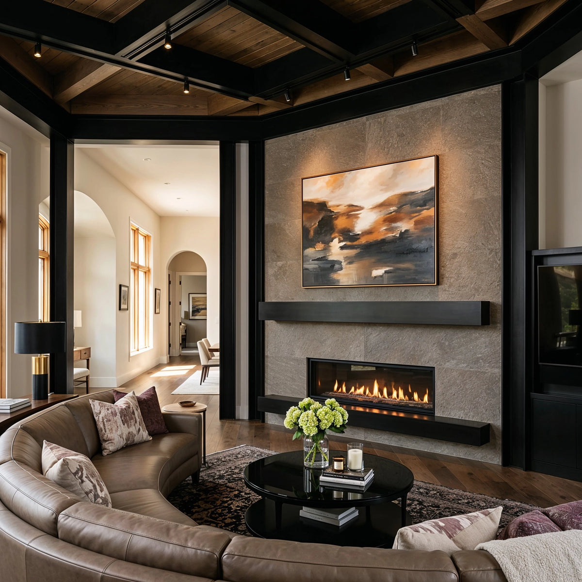 Black living room ideas with black beams and trim, warm wood ceiling, gray stone fireplace, curved taupe sectional, and glossy black coffee table.
