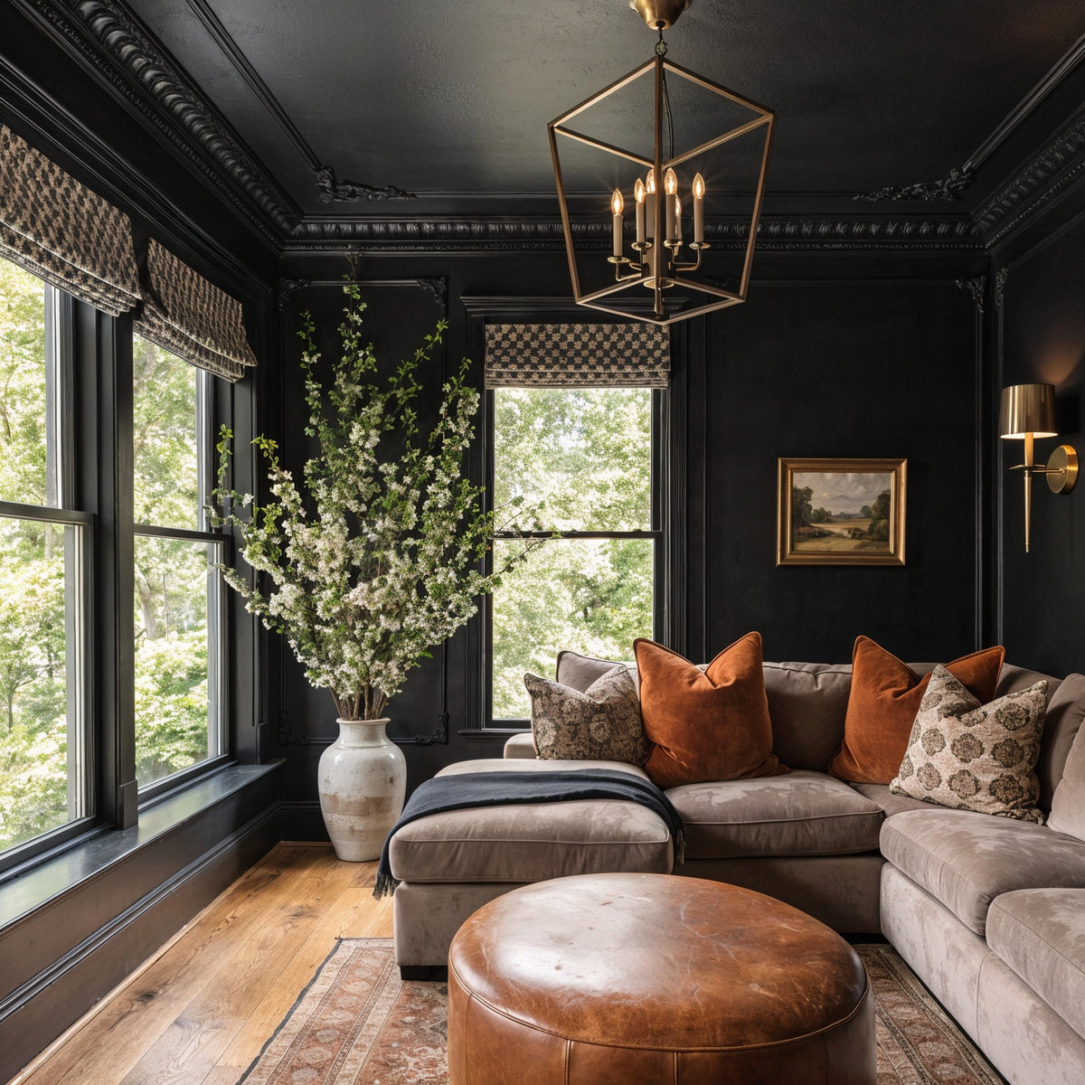 Black living room ideas with ornate black walls and ceiling, taupe sectional sofa, cognac leather ottoman, burnt orange pillows, large windows, and traditional decor.