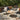 Charmydecor black PE rattan patio set with loveseat, two club chairs, and round acacia wood coffee table on a backyard patio