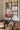 Room interior with wooden shelves, a table with a vase and teapot, and cherry blossom branches.