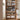 Wooden bookshelf with adjustable shelves, pegboard panel, and cable management hole in a room setting.