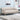 Beige tufted sofa in a living room setting with a light blue wall and decorative items.