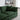 Green sofa in a living room with decorative items on a shelf.