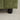 Close-up of a green textured sofa corner with a black leg on a beige carpet.