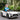 Child in a toy Mercedes-Benz car outdoors with greenery in the background