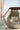 Gold textured vase on a marble surface with a blurred background