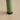 Green cylindrical object with black base on a beige surface