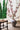 Decorative vase with cherry blossom branches on a wooden floor with a blurred outdoor background