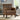 Brown leather armchair in a living room setting with a window and decor in the background.