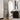 Full-length mirror with gold frame leaning against a wall in a modern interior setting.