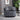 Gray tufted armchair in a living room setting with a plant and wall art.