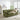 Woman sitting on a green sofa in a bright living room with a fireplace and plants.
