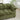 Green sofa in a living room setting with a plant and fireplace.