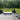 Modern outdoor patio with a curved daybed, chairs, and potted plants in a forest setting.