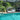 Wicker daybed by a pool with lush greenery in the background