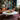 Charmydecor marble round coffee table styled with bar tray in an eclectic living room with leather sofa and gallery wall