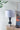 Table lamp with a white shade and black base on a wooden side table against a light wall.