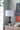 Table lamp with a white shade on a wooden cabinet against a gray wall with abstract art.