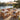 Charmydecor natural acacia wood 7-seater patio furniture set with beige cushions arranged under an umbrella by the lake