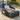 Man sitting on a wicker outdoor lounge with blue cushions on a deck.