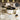 Coffee table set with glossy marble top, gold legs, and drawer on a patterned floor.