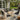 Charmydecor Nusa black PE rattan outdoor patio conversation set with acacia wood table beside an outdoor fireplace