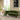 Green sofa in a living room with a round glass coffee table and decorative elements.