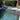 Modern outdoor lounge chair by a pool with greenery in the background