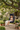 Child sitting in a hanging egg chair on a patio with greenery and a garden setting.
