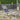 charmydecor Oxton gray wicker patio chaise lounge styled with a blue pillow on an outdoor deck