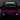 Pink toy car with illuminated headlights and roof light on a dark background