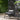 Wicker chair with gray cushions in an outdoor setting with plants and a small table.